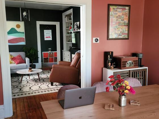 A dining room with coral walls and a wood table, looking through to the living room