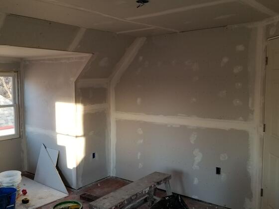 An upstairs room with new drywall hung and taped, ready for finishing