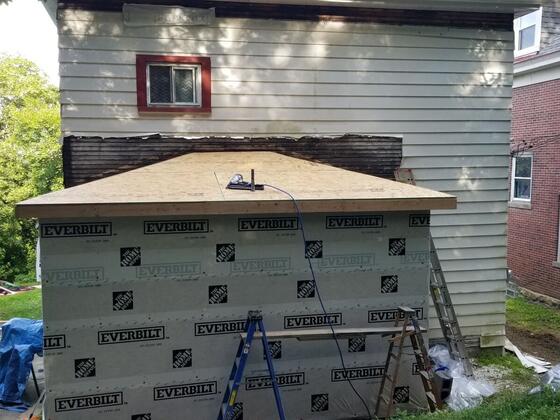 The rear addition from behind the house, wrapped and topped with a new plywood roof deck