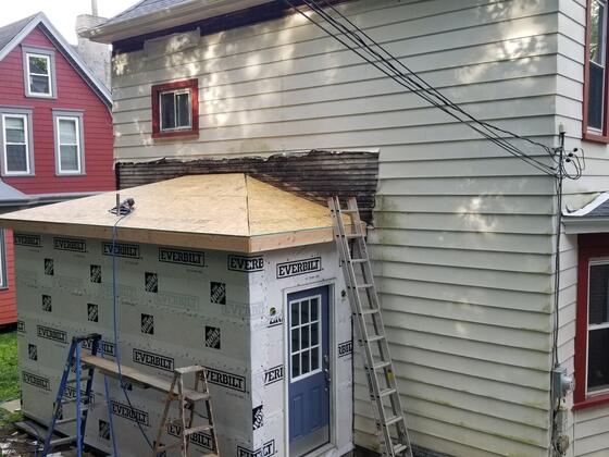 The rear addition from the side, with a new entry door and ladders against the house